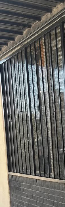 Close-up of black pleated retractable mesh insect screen door on a residential exterior entryway