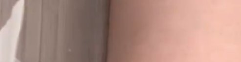 Heavily blurred closeup, left shows vertical taupe curtain, right is out of focus human skin, par...