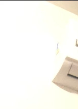 Overexposed blurry indoor view of a bright white interior wall, with partial wall vent and fixtur...