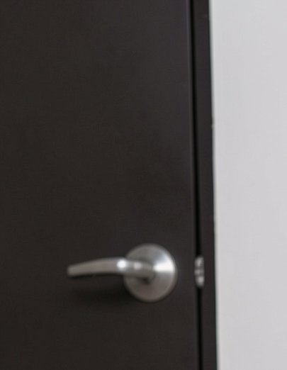 Close-up of a matte dark interior door with a brushed silver lever handle, adjacent to a pale lig...