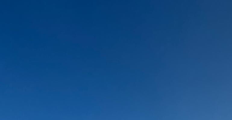 Clear, cloudless vibrant deep blue sky with a subtle soft color gradient, no visible clouds or el...