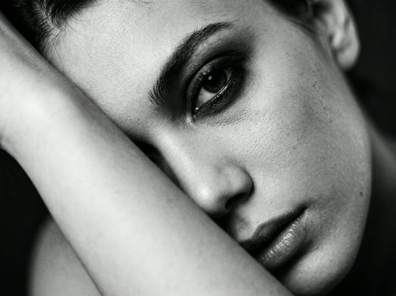 Close-up black-and-white portrait of a woman resting her head on her arm.