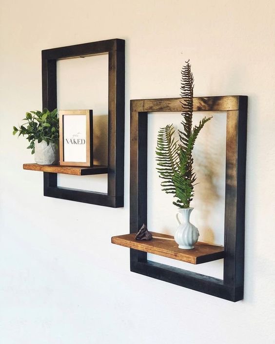 Geometric wall shelves with black frames and wooden shelves displaying plants and decor