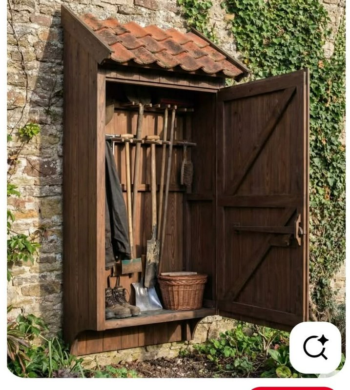 Rustic wooden garden shed with tools hung on a wall and an open door beside a stone wall.