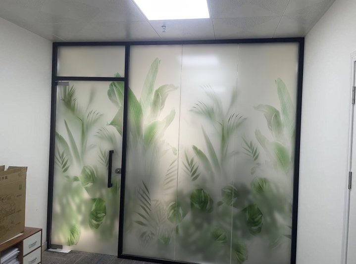 Frosted glass office door with green botanical plant silhouettes and dark frame.