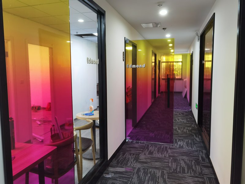 Color-tinted glass corridor in an office with gradient pink, yellow, and purple panels