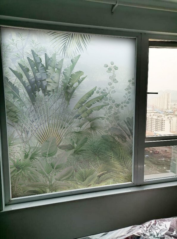 Frosted window with tropical plant pattern obscuring the city view.