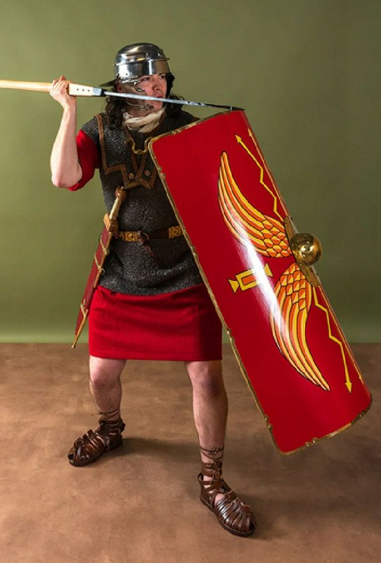 Roman legionary in armor posing with a red shield and spear.