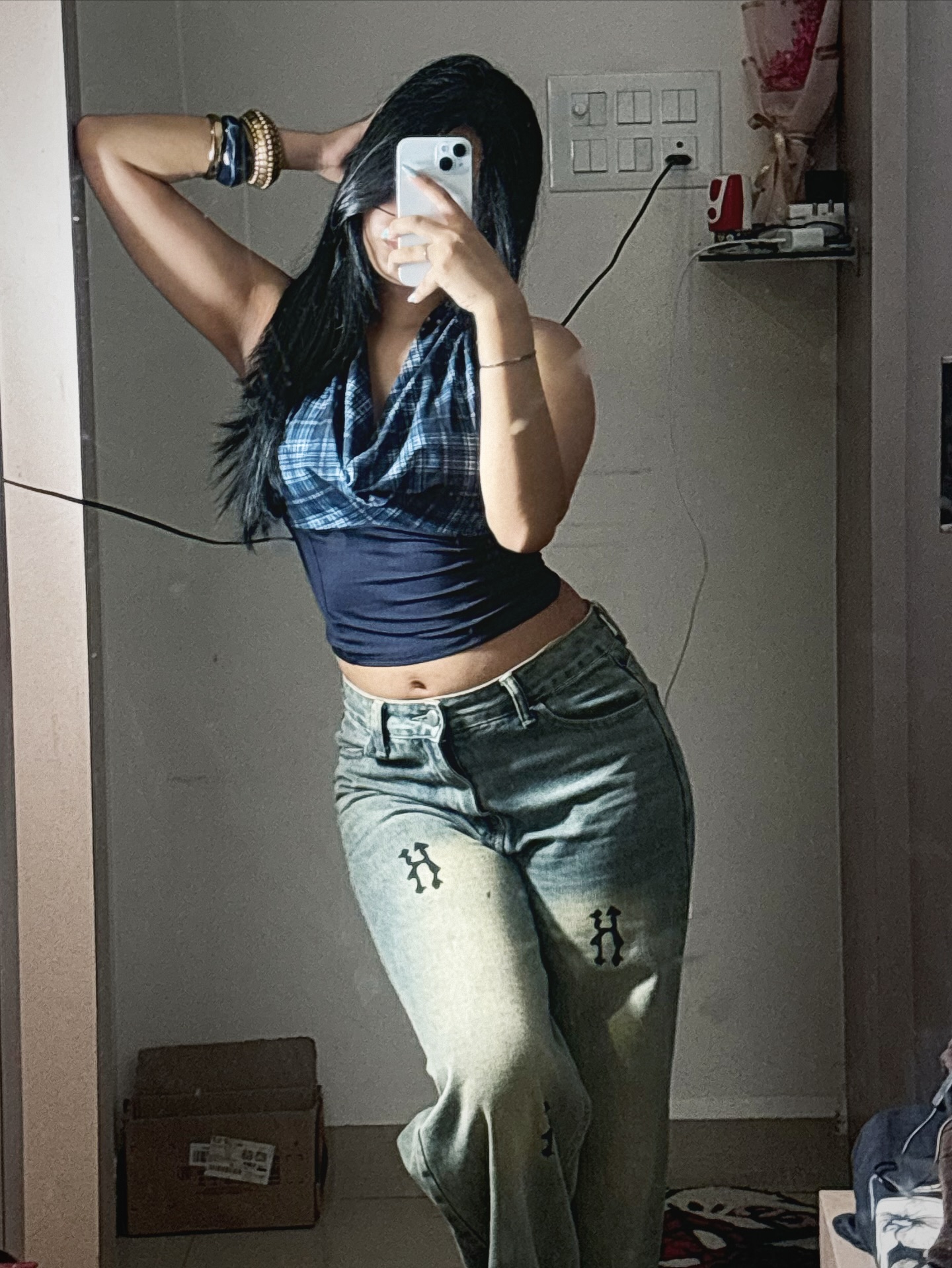 Woman taking a mirror selfie in a blue halter crop top and light-wash jeans.