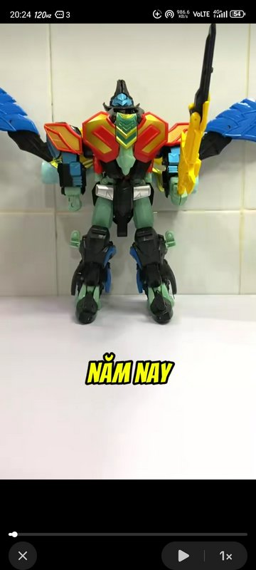 A colorful transformer-style action figure robot standing upright against a tiled wall.