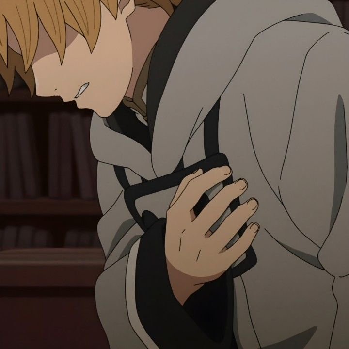 Anime still of blonde Rudeus Greyrat clutching his injured arm, head bowed, in a dim library sett...