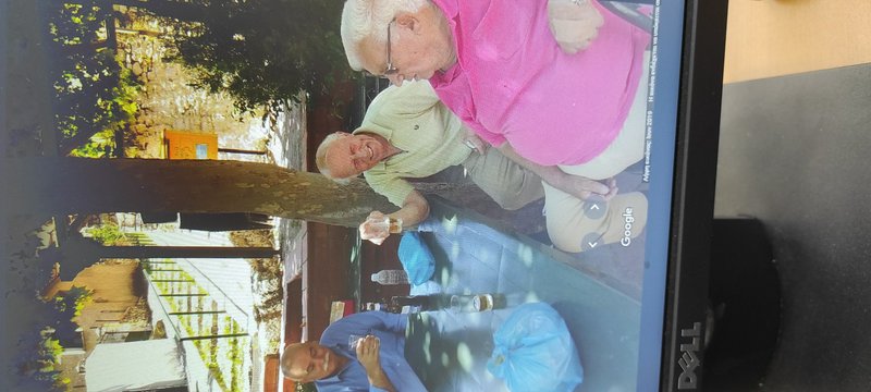 Dell monitor displaying candid photo of three senior men socializing over drinks on a sunny backy...