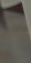 Blurred close-up of an interior room corner, with light neutral walls, angled dark trim, and soft...