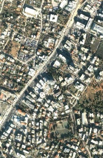Top-down aerial satellite view of a dense suburban urban neighborhood with paved roads, clustered...