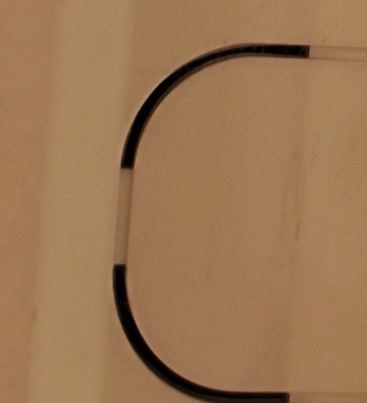 Partial view of two-tone black and silver curved metal frame against soft warm beige fabric backg...