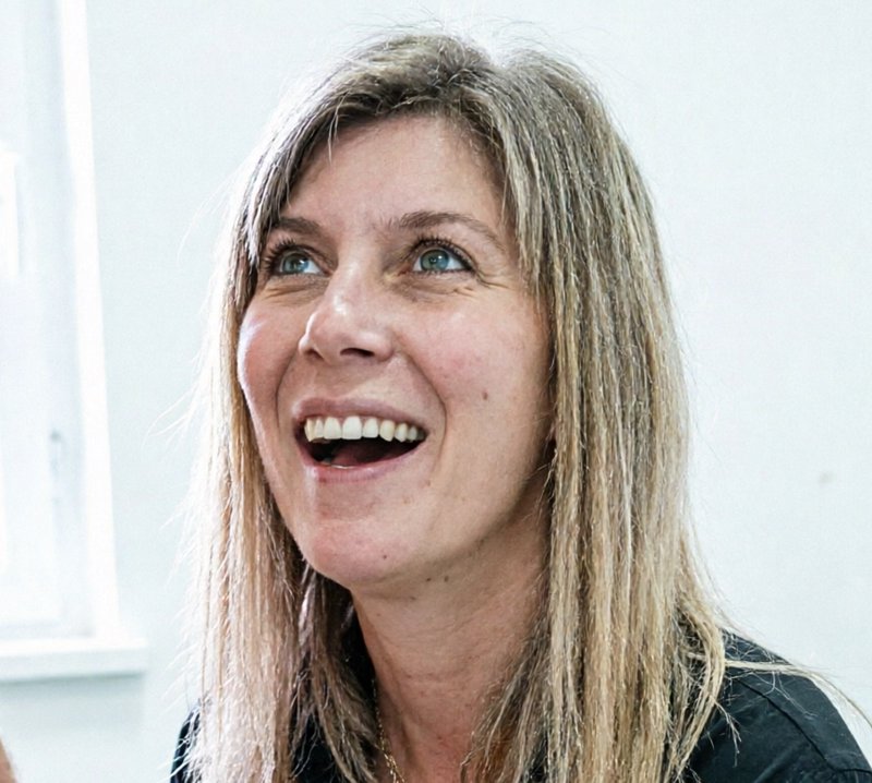 Candid close-up portrait of a joyful middle-aged blonde woman laughing and looking upward in a br...