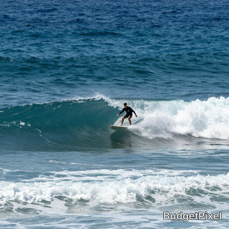Surfer in a black wetsuit carves inside a turquoise breaking ocean wave, riding a white surfboard...