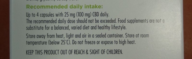 Close-up of a CBD supplement product label showing recommended dosage, storage rules, and child s...