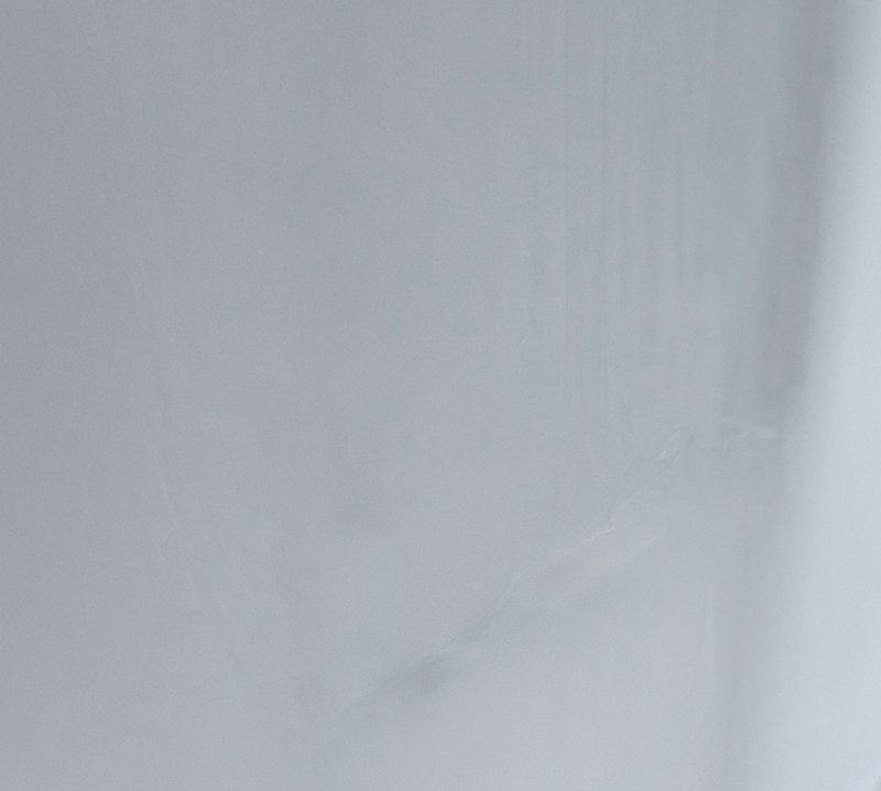 Smooth pale light grey marble surface with faint, delicate wispy natural veining across the frame