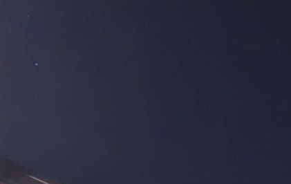 Deep dark navy night sky with two small bright celestial points in the upper left, faint rooftop ...
