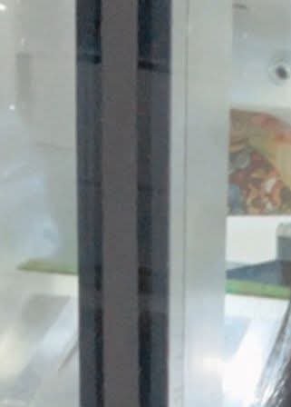 Close-up of a glass door with a vertical dark metal frame and reflective panels