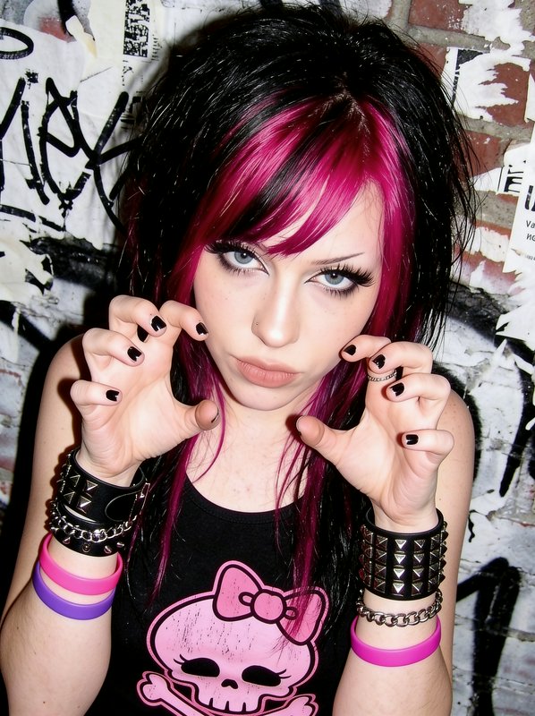 Scene girl with black and hot pink streaked hair making a playful claw hand gesture at the camera