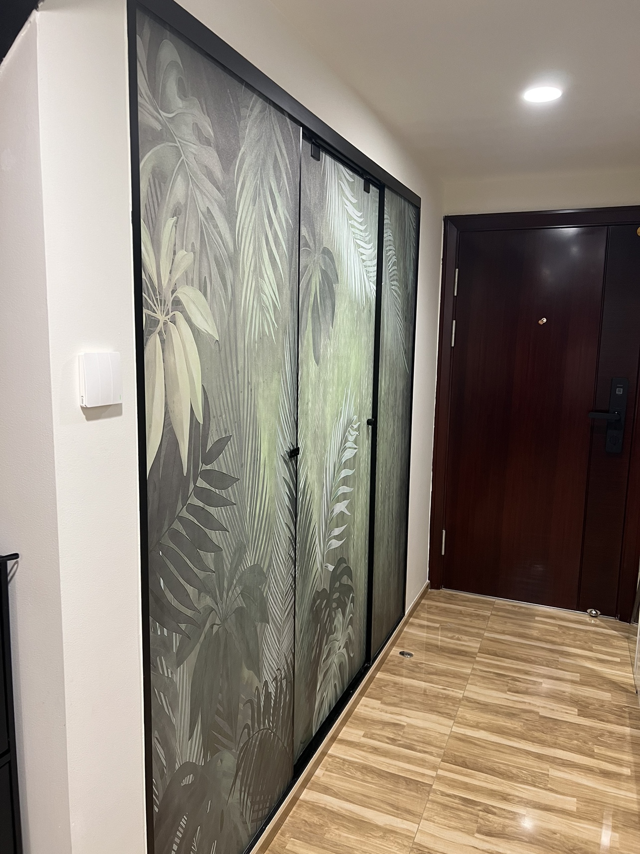 Sliding glass doors with a tropical leaf pattern in a hallway with wood-look flooring.