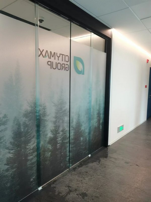Office corridor with frosted glass partition featuring a forest pattern and company logo.
