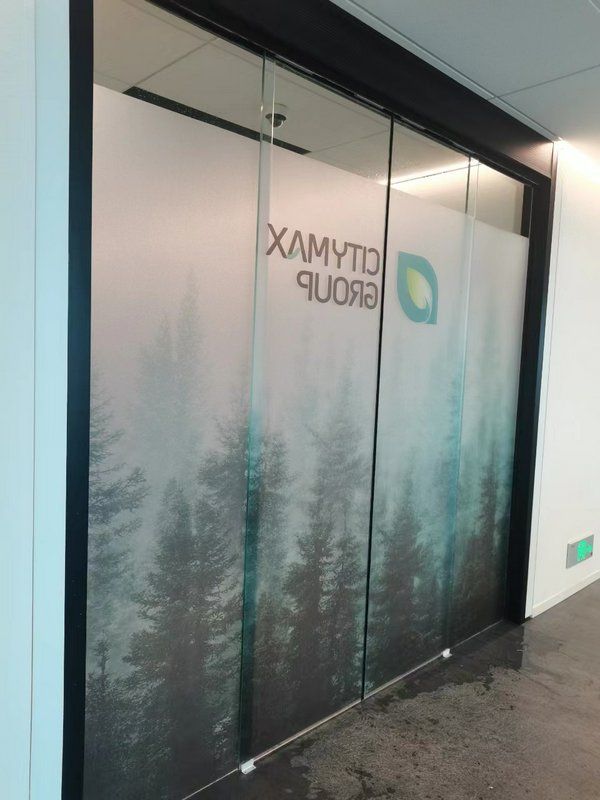 Frosted glass office doors with a forest silhouette design and a small logo.