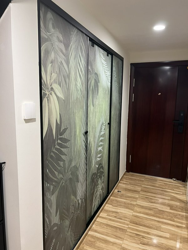 Sliding glass doors with a tropical leaf pattern in a hallway with wood-look flooring.