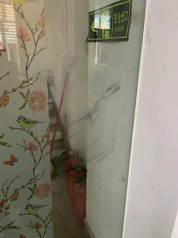 Glass door with floral decal and staircase visible behind, with an exit sign above.
