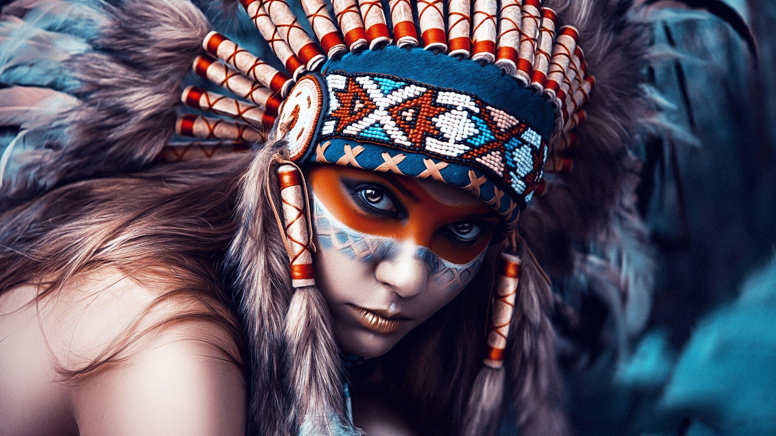 Person wearing a feathered beadwork headdress with bold face paint and intense gaze.