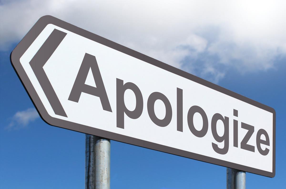 Directional road sign with the word "Apologize" against a blue sky.
