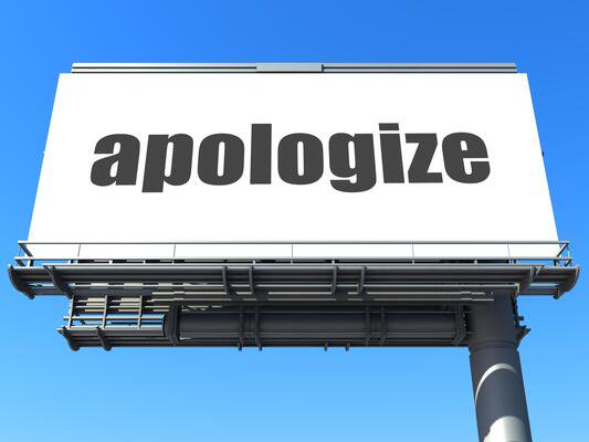 Large billboard with the word "apologize" against a bright blue sky.