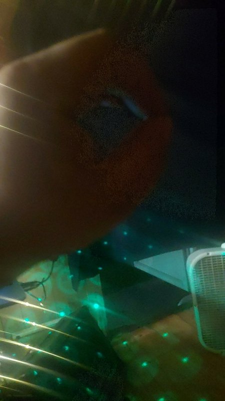 Dark indoor scene with green laser dots, a hand in the foreground, and a microphone on the right.