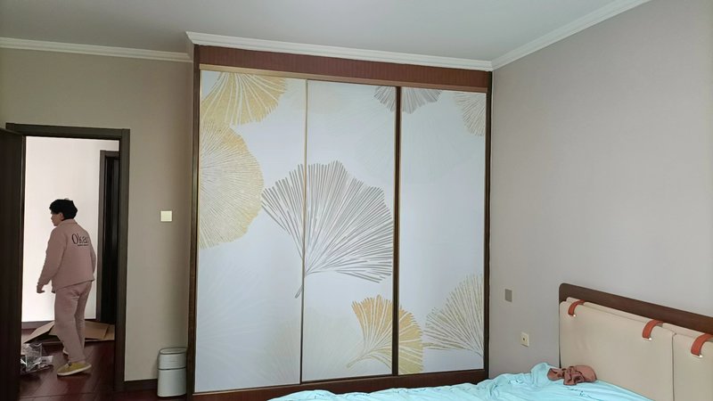 Bedroom with sliding wardrobe doors featuring fan-pattern panels and soft, neutral walls.