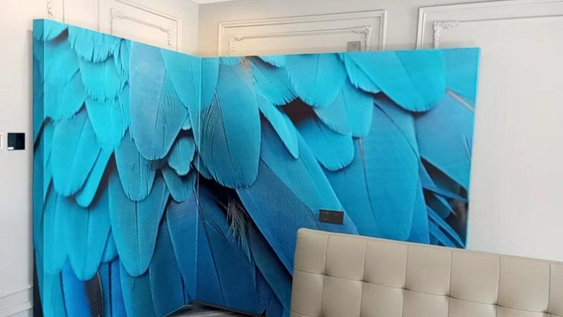 Large blue feather wall mural in a modern room with a beige tufted sofa.