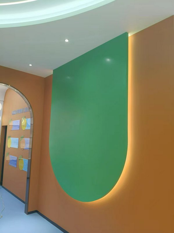 Modern interior with a large green curved wall panel on an orange wall, edge-lit for a warm glow.