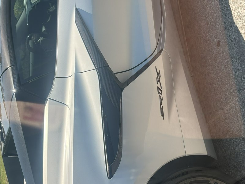 Close-up side view of a silver Chevrolet Corvette Z06 showing its carbon fiber side vent and Z06 ...