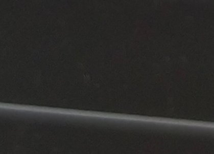 Close up of a grainy, turned-off dark display screen with a thin silver monitor bezel running alo...