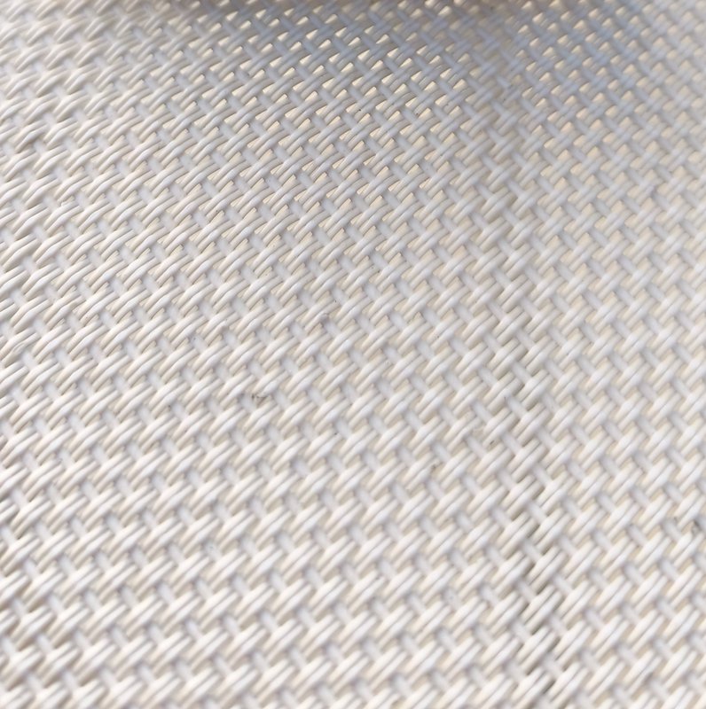 Macro close-up of pale off-white diagonal herringbone woven mesh fabric, showing uniform interlac...