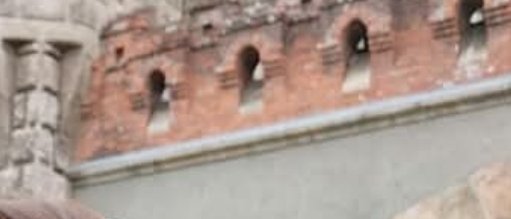 Blurred tilted view of a historic red brick fort wall with small arched defensive openings