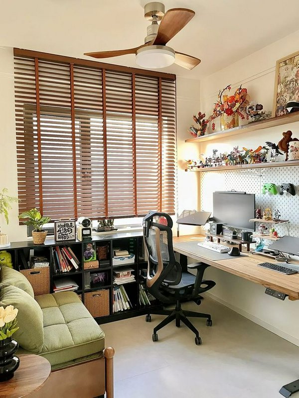 Sunlit cozy home office workspace with wooden desk, gaming setup, collectible shelves, window bli...