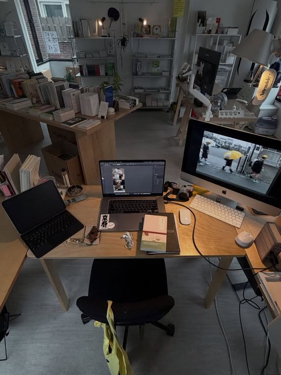 High-angle view of a cozy creative home office desk with computers, notebooks, and bookshelves in...