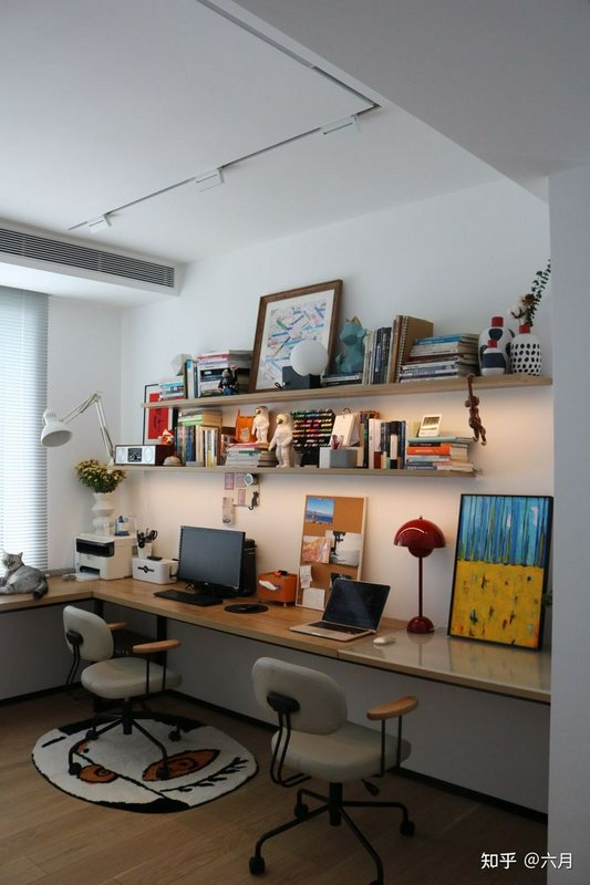 Bright modern home office with floating shelves, dual desk setup, office chairs, and a cat restin...