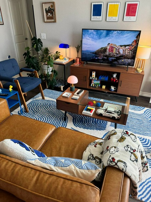 Cozy playful midcentury modern living room with Snoopy decor, warm wood furniture and vibrant col...
