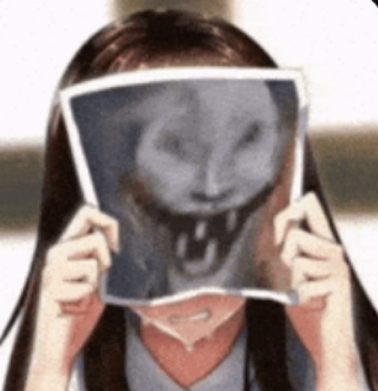 Person holds a paper with a creepy grayscale grinning face, obscuring their own face.