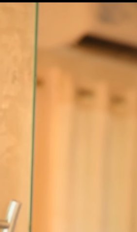 Blurry close-up of a glass edge with warm, out-of-focus interior background.