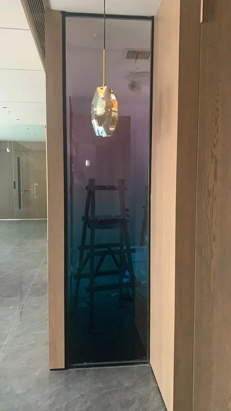 Interior hallway with wooden-framed panels, a tall tinted glass pane, and a geometric pendant light.