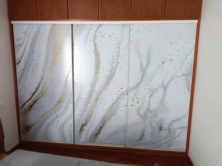 Sliding wardrobe doors with marble-pattern panels in a wooden frame.